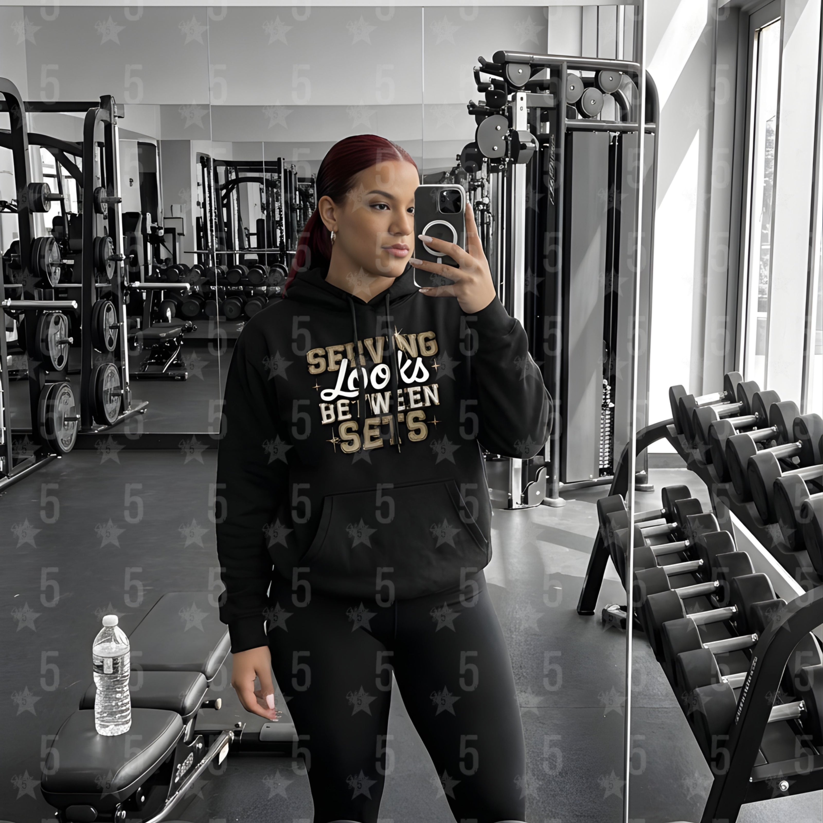 a woman taking a selfie in the gym mirror with a black fitness hoodie