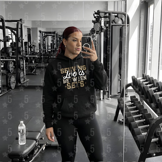 a woman taking a selfie in the gym mirror with a black fitness hoodie