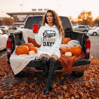 Woman in a truck bed with pumpkins and a 'Heavy on the Grace & Game Day' sweatshirt.