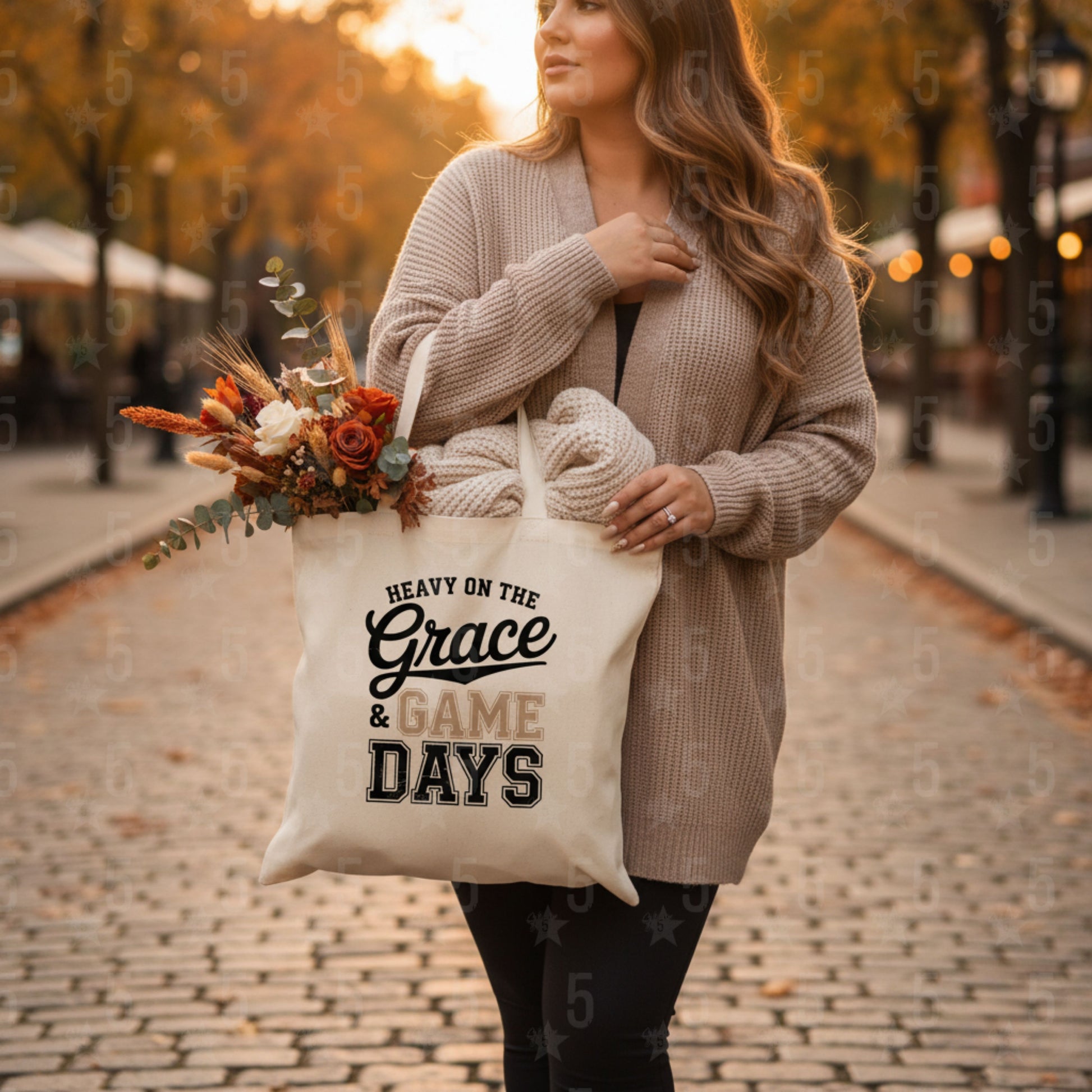 Woman holding a tote bag with text and flowers, standing on a street with autumn foliage.