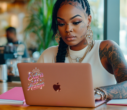Woman with tattoos using a laptop with 'Extra AF Always' sticker in a casual setting