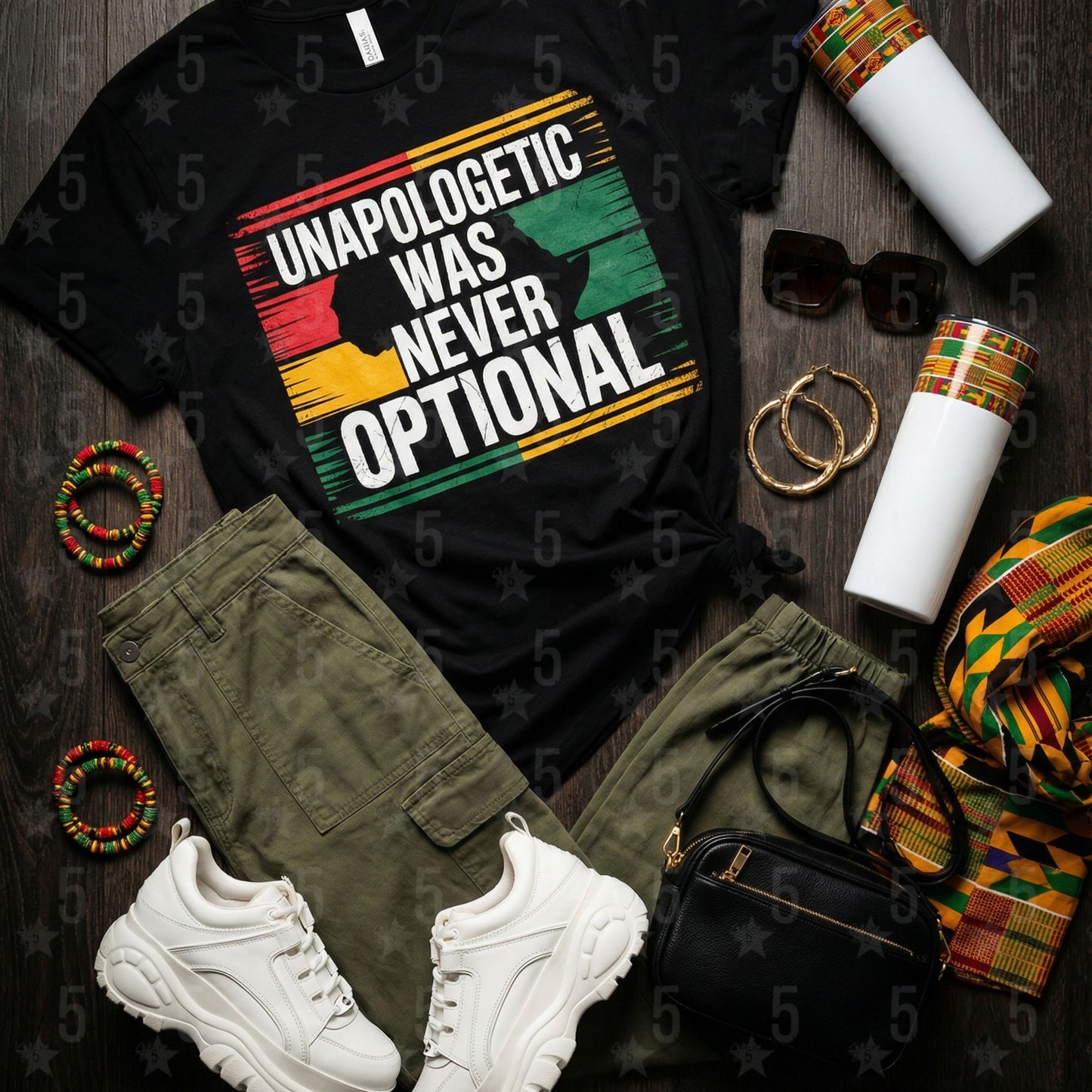 Black t-shirt with 'Unapologetic Was Never Optional' design, green pants, white sneakers, and accessories on a wooden surface.
