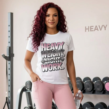 Woman in a gym wearing a 'Heavy Weight, Light Work' t-shirt and pink leggings.