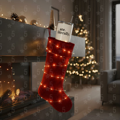 Red Christmas stocking with lights and a tumbler labeled 'ate. literally.' in a festive room.