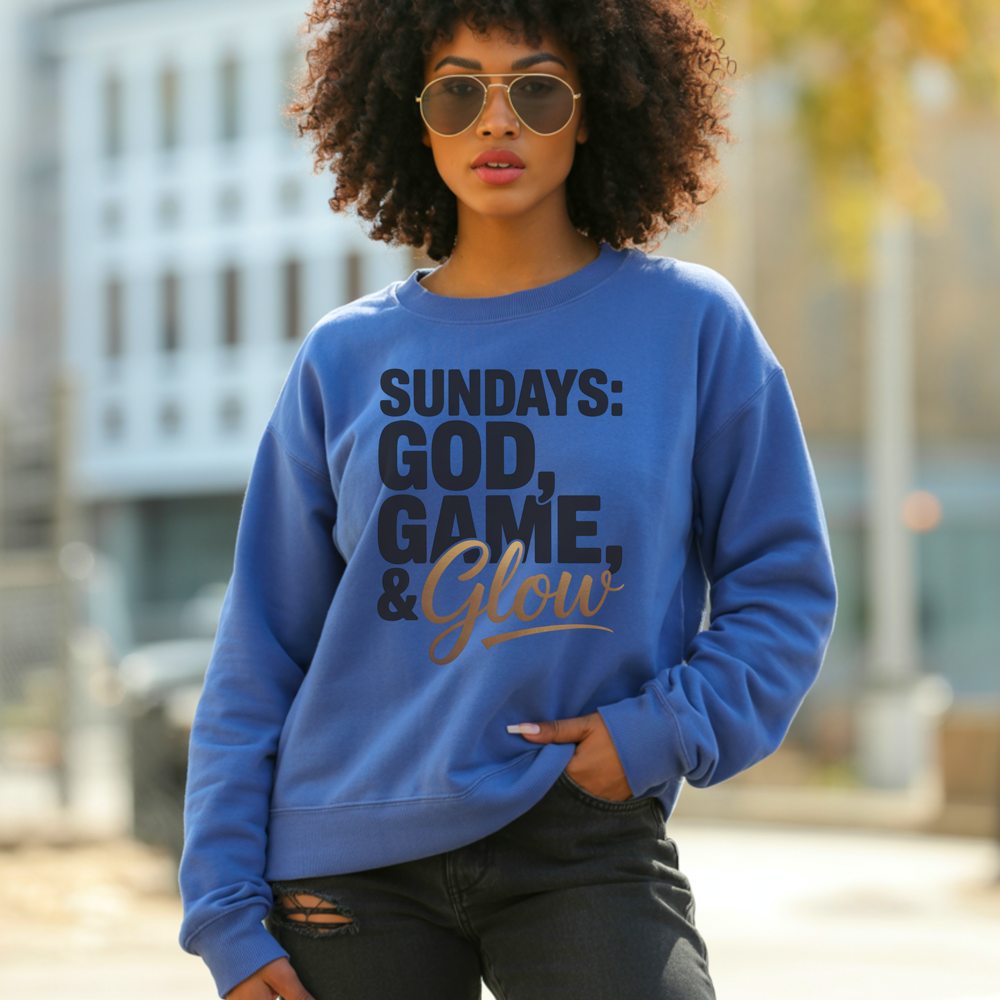 Woman wearing a blue sweatshirt with sundays god game glow design standing outdoors