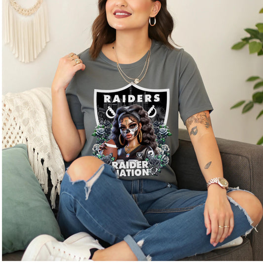 Woman wearing a t-shirt with a dia de los muertos Raiders design sitting on a couch.