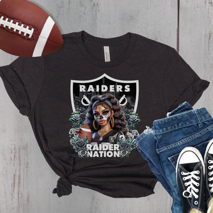Black t-shirt with a dia de los muertos Raiders design, football, jeans, and sneakers on a wooden surface.