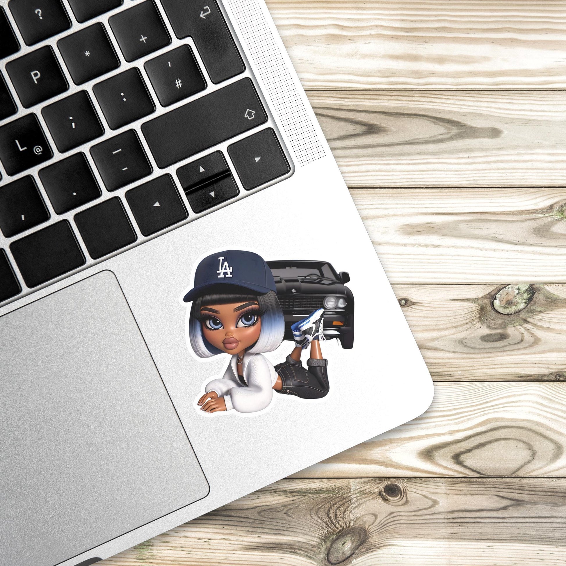 Laptop with a sticker of a character wearing a Los Angeles cap on a wooden surface