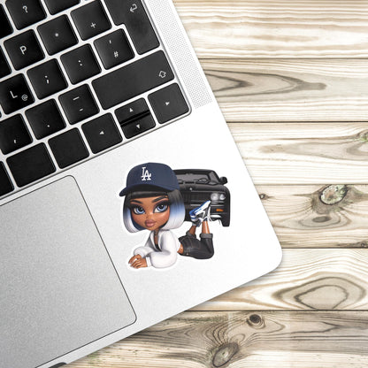 Laptop with a sticker of a character wearing a Los Angeles cap on a wooden surface