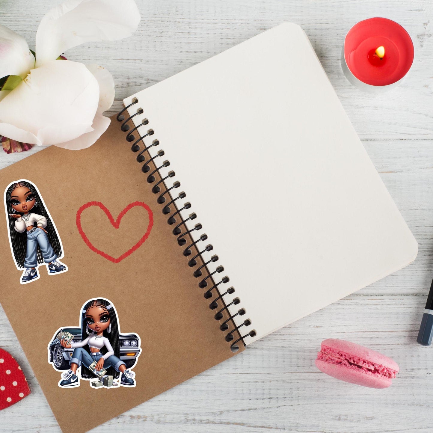 Notebook with gnx bratz doll stickers and decorative items on a light wooden surface