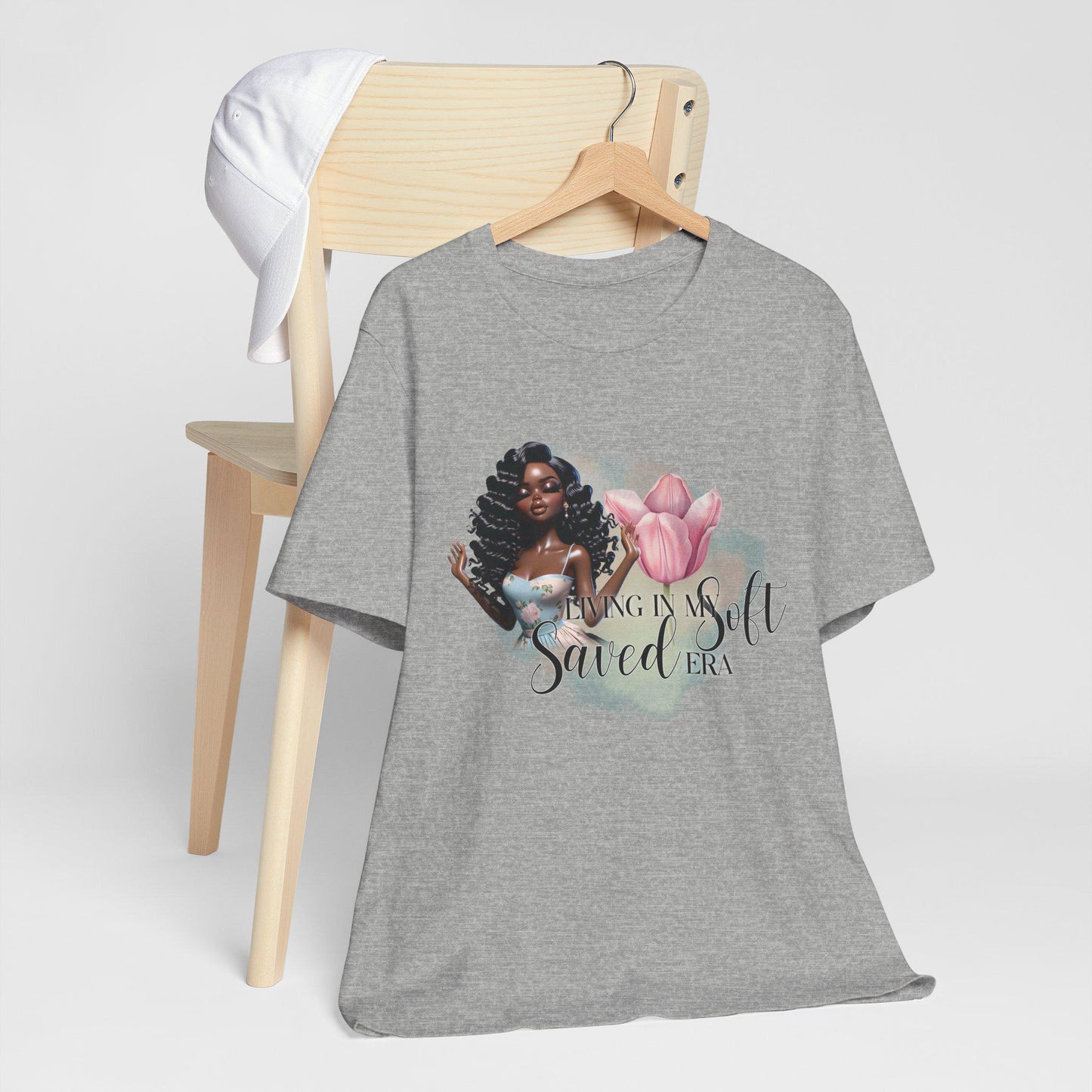 Gray t-shirt with a graphic design of a woman and text, hanging on a wooden chair.