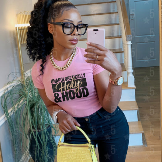 Woman taking a mirror selfie wearing a pink t-shirt with text, standing in a home setting.