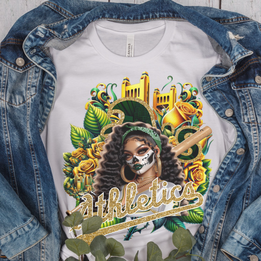 T-shirt with a colorful dia de los muertos Athletics design featuring a woman with a skull mask, roses, and 'athletics' text, displayed on a denim jacket.