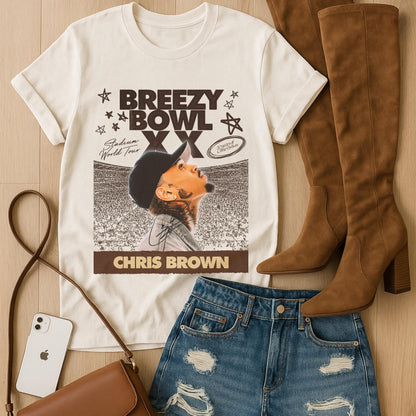 White t-shirt with with Breezy Bowl graphic, brown knee-high boots, blue jeans, and brown handbag on a wooden surface.