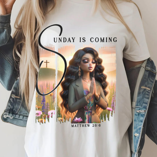 Person wearing a white t-shirt with a sunday is coming design, standing against a plain background.