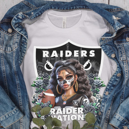 White t-shirt with a dia de los muertos Raiders design, displayed inside a denim jacket.