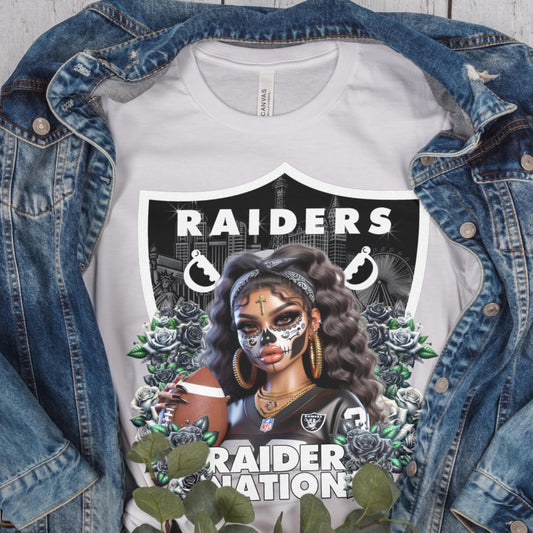 White t-shirt with a dia de los muertos Raiders design, displayed inside a denim jacket.