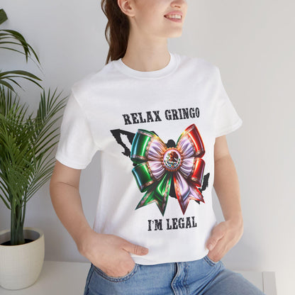 Person wearing a white t-shirt with a Mexican bow and Relax Gringo I'm Legal text in a home setting.