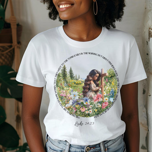 Person wearing a white t-shirt with a graphic design of a woman by a cross and flowers, with text around it.