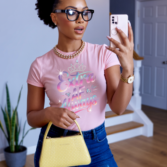 Woman taking a selfie indoors wearing a pink t-shirt with colorful text and blue jeans.