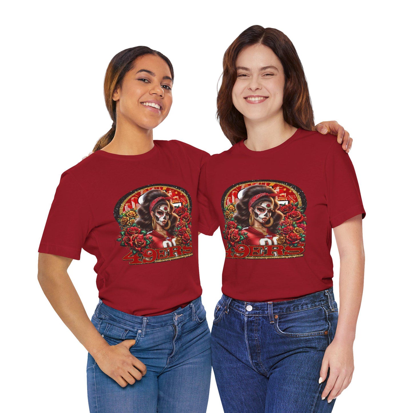 Two women wearing red t-shirts with a dia de los muertos niners design on a white background